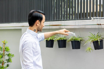 年轻的但浇水植物盆栽植物可回收的塑料瓶浇水植物扭曲的塑料瓶回收年轻的男人。工作花园