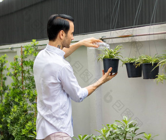 年轻的但浇水植物盆栽植物可回收的<strong>塑料瓶</strong>浇水植物扭曲的<strong>塑料瓶</strong>回收年轻的男人。工作花园
