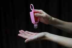 手持有人粉红色的硅胶洗手液过来这里瓶电晕病毒