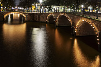 照亮阿姆斯特丹运河桥反映了平静运河水阿姆斯特丹晚上