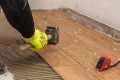 工人放置陶瓷地板上瓷砖胶粘剂表面水准测量