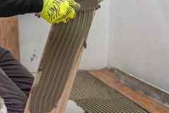 工人放置陶瓷地板上瓷砖胶粘剂表面