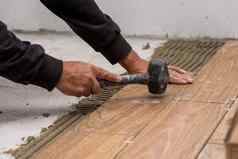 工人放置陶瓷地板上瓷砖胶粘剂表面水准测量