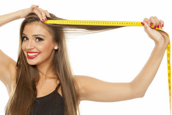 年轻的快乐美丽的女人测量头发