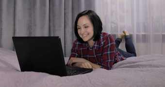 年轻的女人说谎床上视频闲谈，聊天网络摄像头移动PC电脑