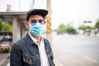 亚洲年轻的男人。站城市穿保护面具