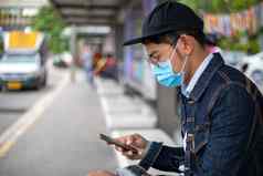 亚洲年轻的男人。聪明的电话城市穿脸面具保护空气污染微粒保护流感病毒流感冠状病毒