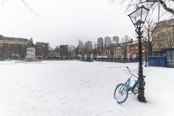自行车锁着的灯帖子中央的地方覆盖雪满荷兰拥挤的人用餐者喝日落温暖的天气黑格荷兰
