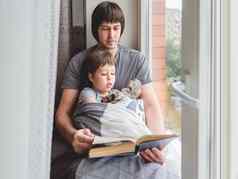 父亲读取书儿子舒适的家庭时间窗台上whi