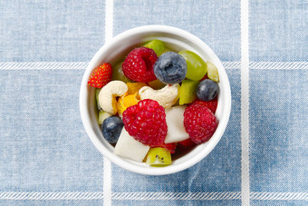 新鲜的水果沙拉白色碗混合水果白色碗健康的食物风格水果沙拉新鲜的水果浆果粉红色的背景碗水果沙拉