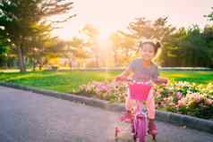 可爱的亚洲女孩骑自行车锻炼公园