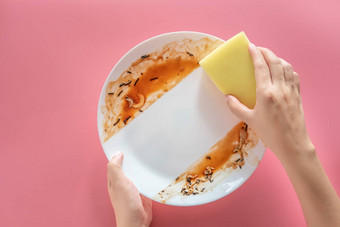 女人黄色的清洁海绵清洁洗食物污渍污垢白色菜吃餐孤立的粉红色的背景清洁医疗保健环境卫生首页概念