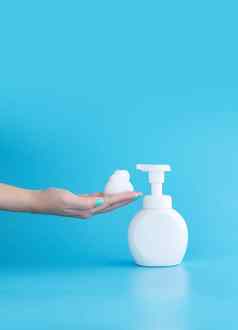 塑料泵瓶摩丝泡沫清洗泡沫女人手孤立的蓝色的背景垂直复制空间清洁概念