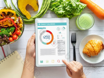 卡路里计数饮食食物控制重量损失概念女人卡路里计数器应用程序平板电脑餐厅表格新鲜的蔬菜沙拉