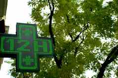 发光的绿色交叉药店标志指示开放十二个小时