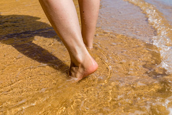 女人走光着脚海滩关闭腿年轻的女人