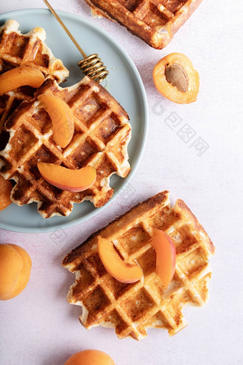 新鲜的自制的比利时华夫饼杏子蜂蜜蓝色的板前视图平躺