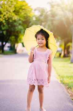 女孩粉红色的衣服黄色的伞阳光明媚的一天
