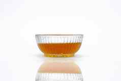 生有机蜂蜜花蜜透明的玻璃碗反射孤立的白色