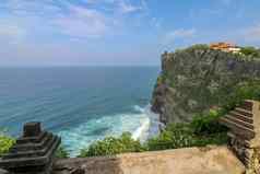 视图Uluwatu悬崖展馆蓝色的海巴厘岛印尼美丽的风景普拉崇高Uluwatu寺庙色彩斑斓的花前景一天风景优美的沿海景观高悬崖