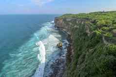 视图Uluwatu悬崖展馆蓝色的海巴厘岛印尼美丽的风景普拉崇高Uluwatu寺庙色彩斑斓的花前景一天风景优美的沿海景观高悬崖