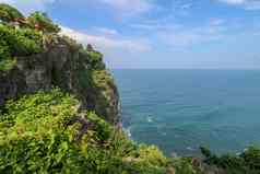 视图Uluwatu悬崖展馆蓝色的海巴厘岛印尼美丽的风景普拉崇高Uluwatu寺庙色彩斑斓的花前景一天风景优美的沿海景观高悬崖