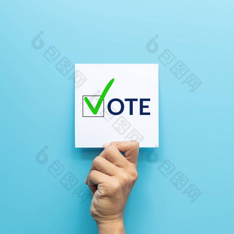 手持有白色纸投票绿色检查马克投票符号复选框登记孤立的蓝色的背景