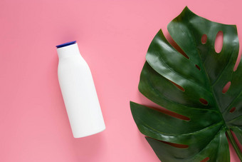 化妆品自然护肤品概念白色化妆品瓶容器空白标签品牌模拟装修绿色热带叶子粉红色的背景复制空间