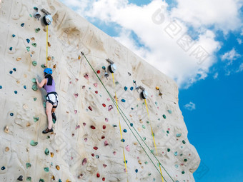 亚洲运动女人练习岩石攀爬岩石<strong>墙</strong>户外<strong>活动</strong>蓝色的天空背景低角视图
