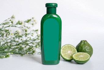 自然产品头发概念绿色塑料瓶空白标签Herbal佛手柑洗发水装修幻灯片非洲高粱酸橙非洲高粱叶白色花白色背景
