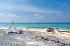 浪漫的白色野餐帐篷白色沙子海滩水晶清晰的水蓝色的天空背景