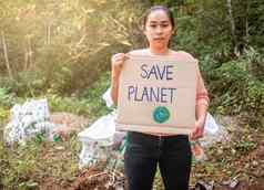 年轻的女人持有保存地球海报显示标志抗议塑料污染森林概念世界环境一天浪费