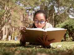 年轻的亚洲女人放松阅读书说谎草优荣亚洲女人放松阅读书说谎草花园假期一天
