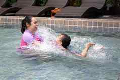 快乐亚洲家庭享受夏天假期游泳池度假胜地