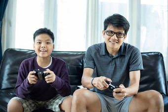 亚洲父亲儿子享受玩视频游戏视频操纵杆激发有趣的生活房间首页
