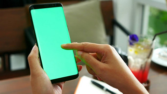 女人手持有移动聪明的电话空白绿色屏幕手指幻灯片绿色屏幕咖啡馆商店喝背景