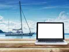 电脑移动PC空白白色屏幕木表格游艇船浮动海背景旅行假期概念