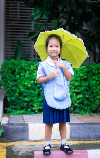 女孩泰国学校统一的黄色的伞raini