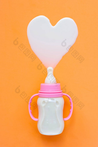 瓶牛奶婴儿橙色背景牛奶心形状前视图