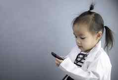 亚洲女孩角色玩医生占领穿白色礼服统一的微笑持有电话玩学习孩子们