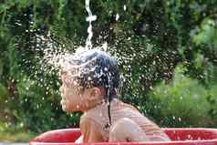 可爱的亚洲孩子女孩有趣的玩水喷涂软管夏天花园