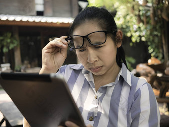 业务亚洲年轻的女人持有移动PC忙工作眼睛问题移动PC长时间