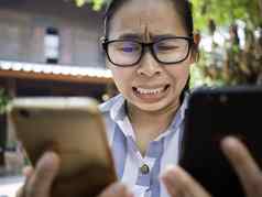 业务亚洲年轻的女人持有智能手机忙工作不开心担心脸