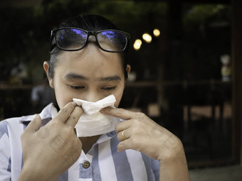 亚洲年轻的女人华林眼镜眼睛刺激撕裂组织纸擦眼泪健康医疗概念