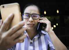 强调业务亚洲年轻的女人持有智能手机工作会说话的电话咖啡咖啡馆不开心脸