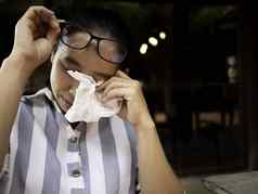 亚洲年轻的女人华林眼镜眼睛刺激撕裂组织纸擦眼泪健康医疗概念