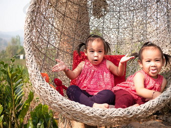 亚洲女孩妹妹坐着白色椭圆形形状的木织椅子公园可爱的脸