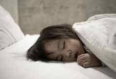 亚洲孩子女孩睡觉床上舒适的健康护理概念