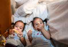亚洲孩子女孩妹妹吃零食美味地用力推床上房间