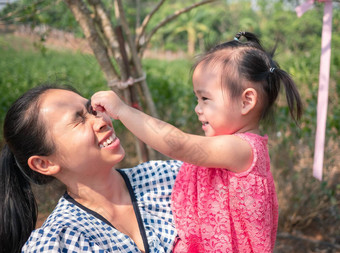 亚洲女孩使有趣<strong>的</strong>脸<strong>妈妈</strong>假装<strong>妈妈</strong>。<strong>妈妈</strong>持有走花园